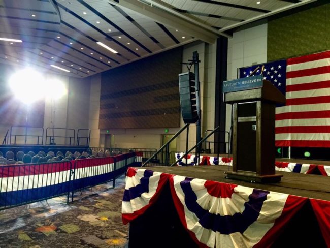 A podium with american flags on it in an empty room.