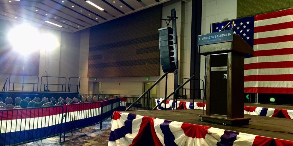 A podium with american flags on it in an empty room.