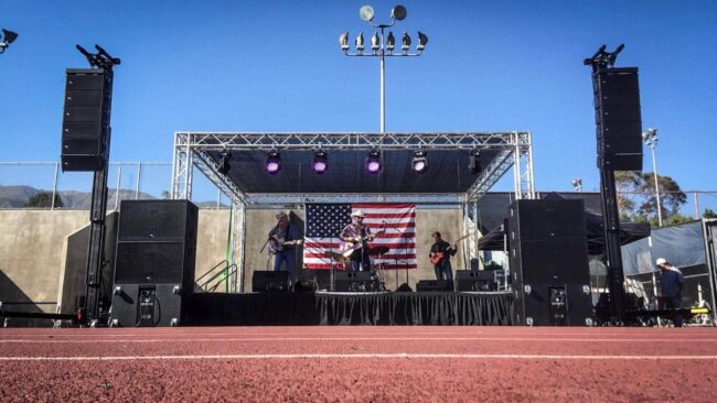 A band performing on stage under an american flag.